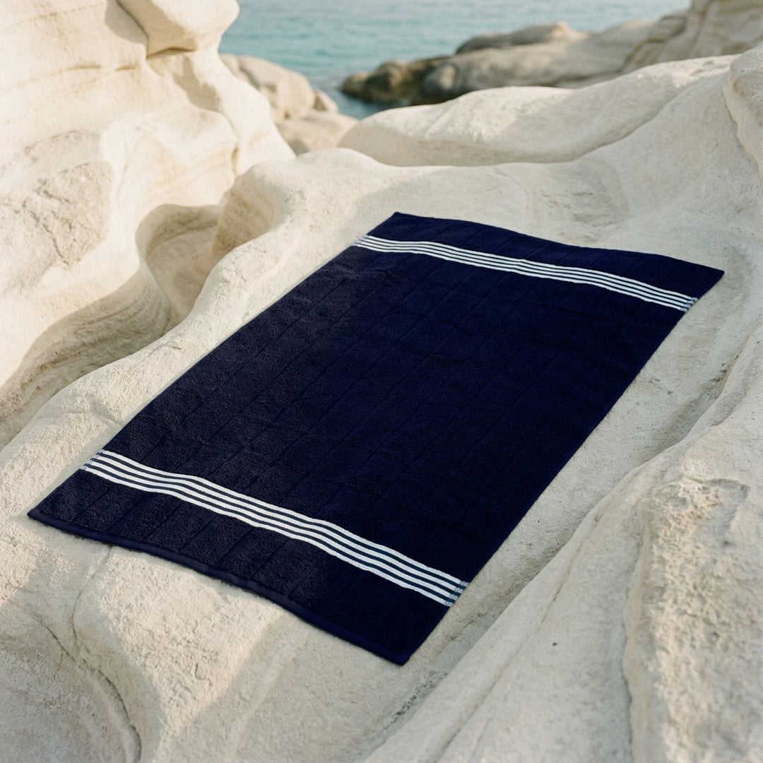 Navy cotton towel laid flat with white stripe border
