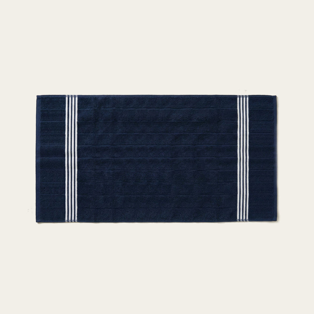 Navy cotton hand towel, flat with white twin stripe border at both sides