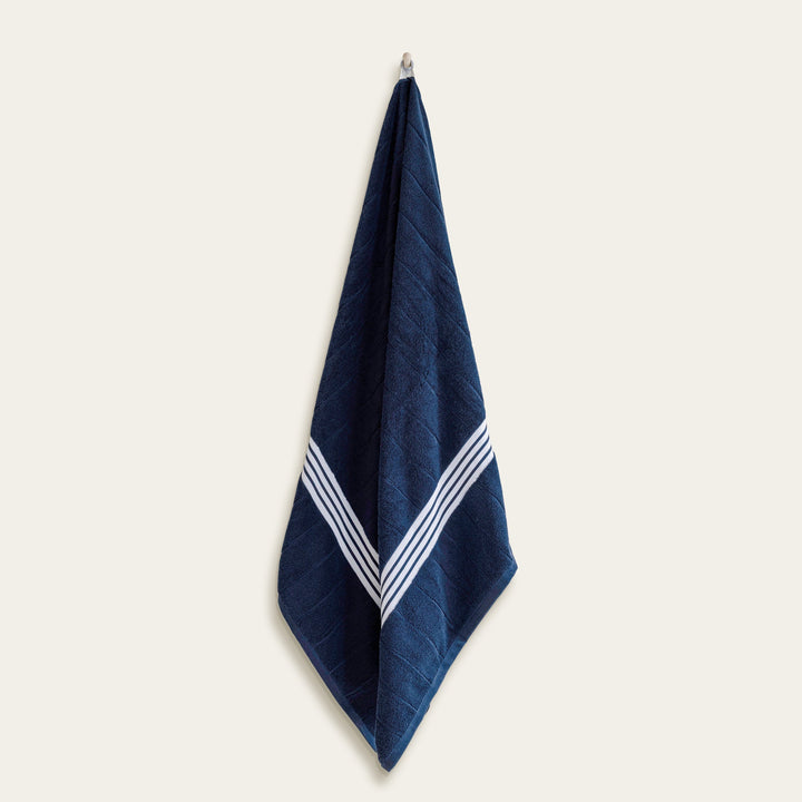 Single folded navy cotton towel hanging with white stripe border
