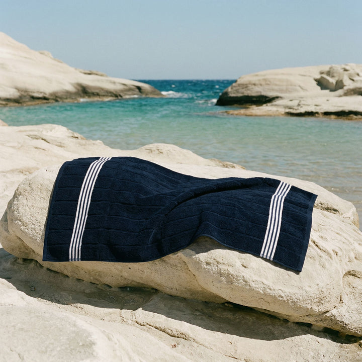 Navy cotton towel draped over a rock with white stripe border