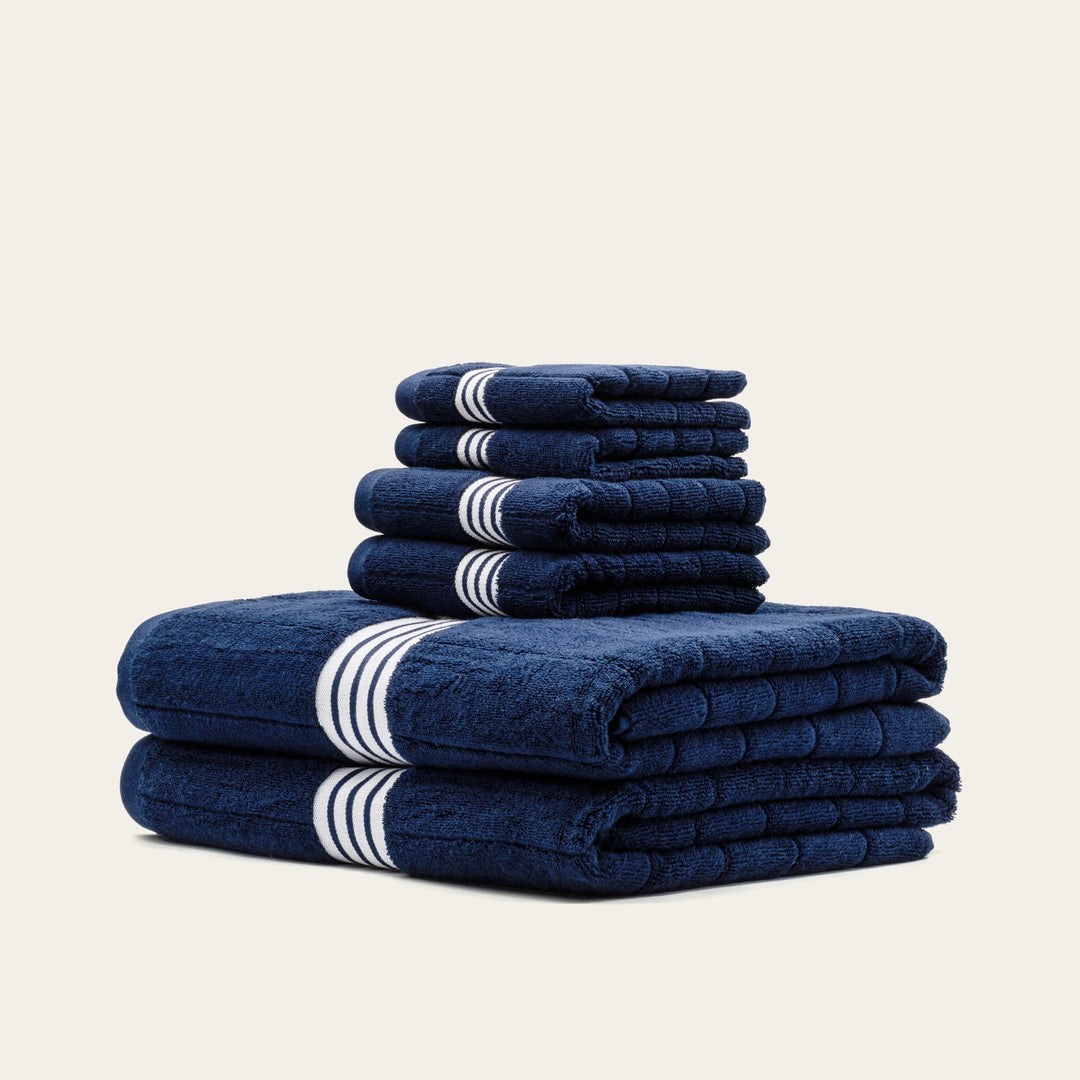 Stack of folded navy cotton towels with white striped bands