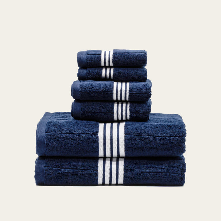 Folded navy cotton towels with white stripe bands in 3 layers