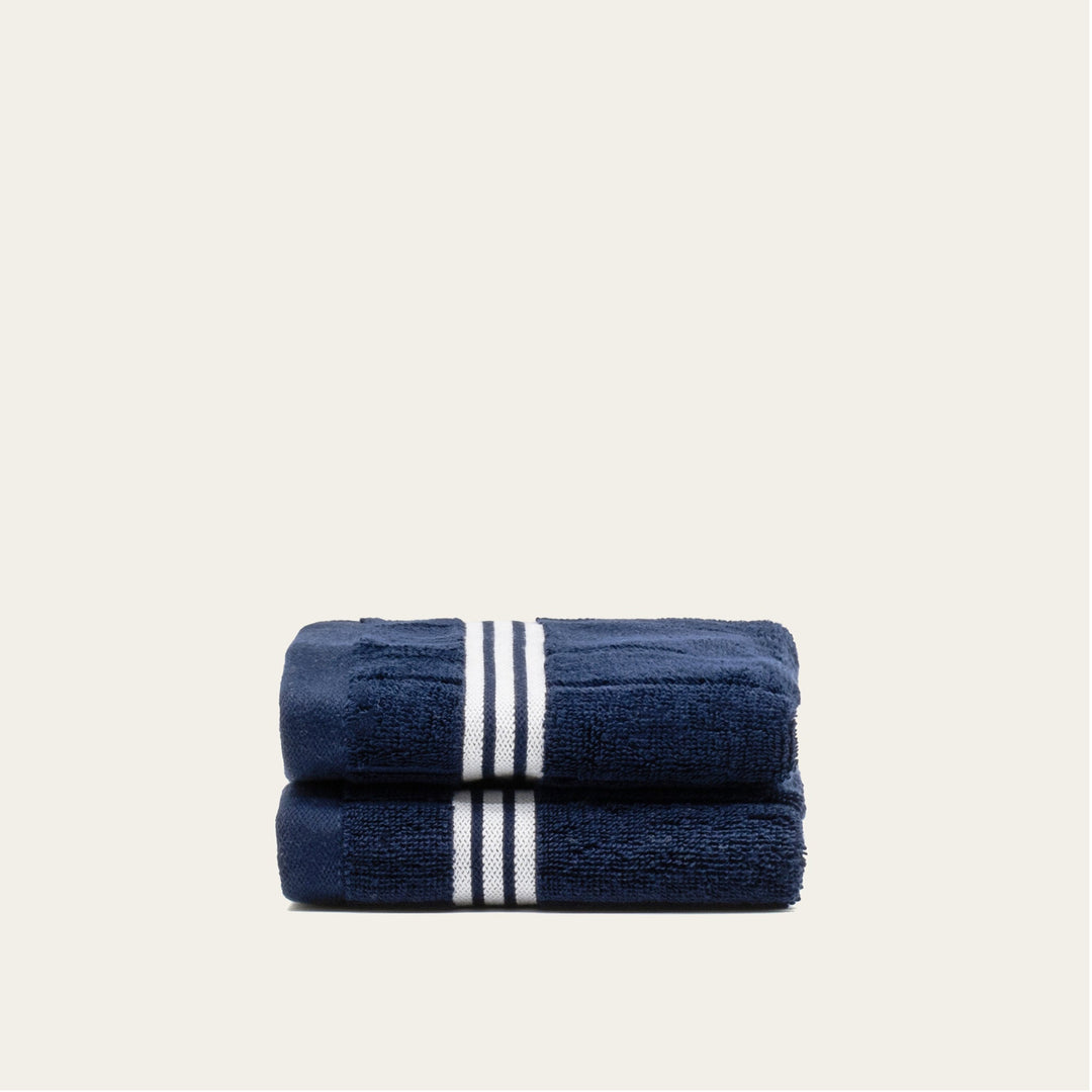 Navy cotton towels, folded stack with two vertical white stripe accents