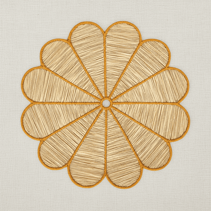 Handwoven iraca flower placemat with purple-stitched petals and a natural woven center.