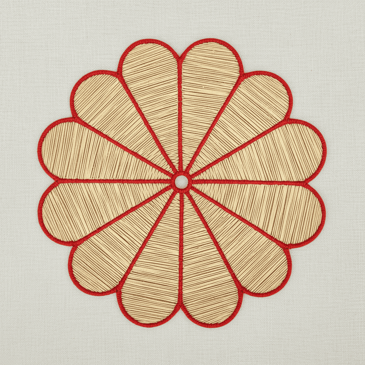 Handwoven iraca flower placemat with teal-stitched petals and a natural woven center.