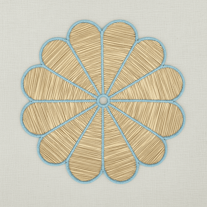 Handwoven iraca flower placemat with blush pink-stitched petals and a natural woven center.