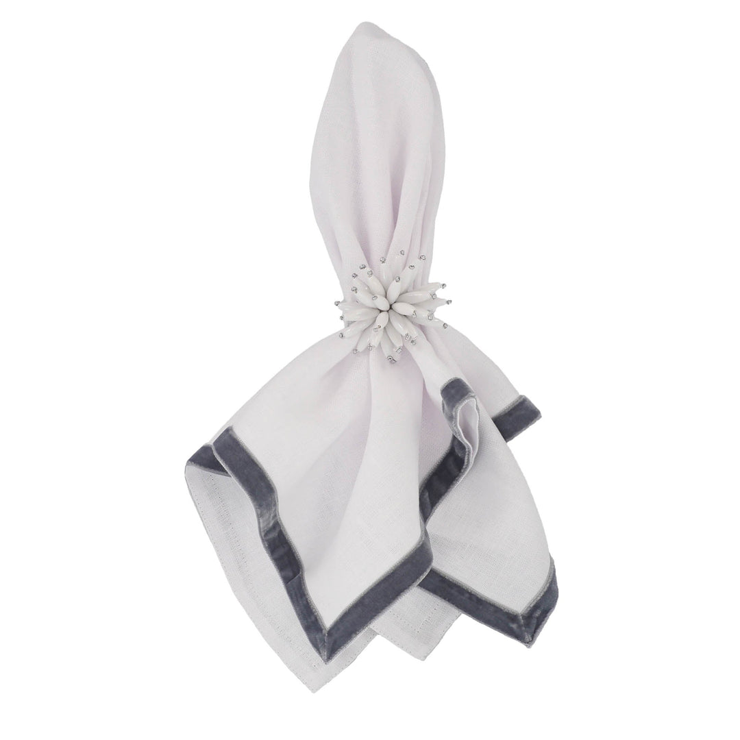 Linen napkin folded and fastened with a white flower clip, dark velvet border