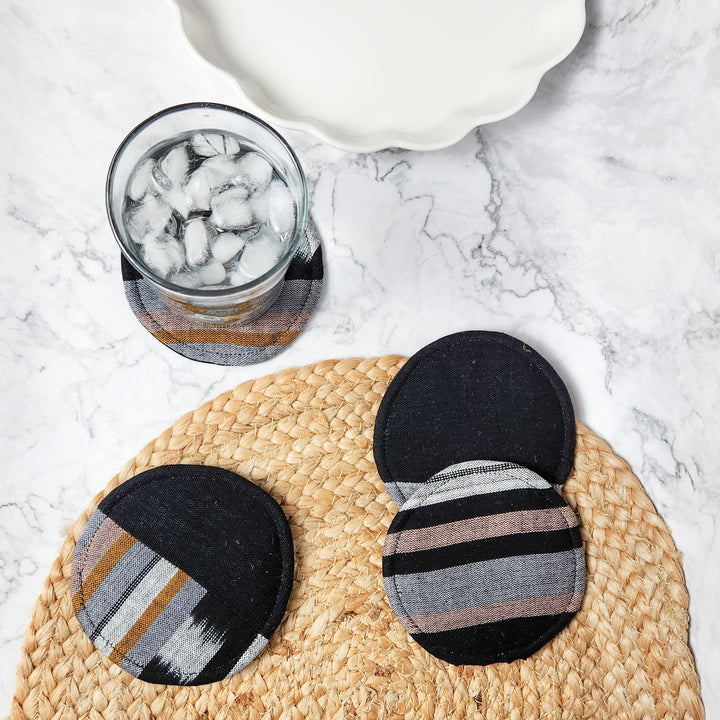 Circular woven coasters set; black round coasters with striped accents and orange/brown weave