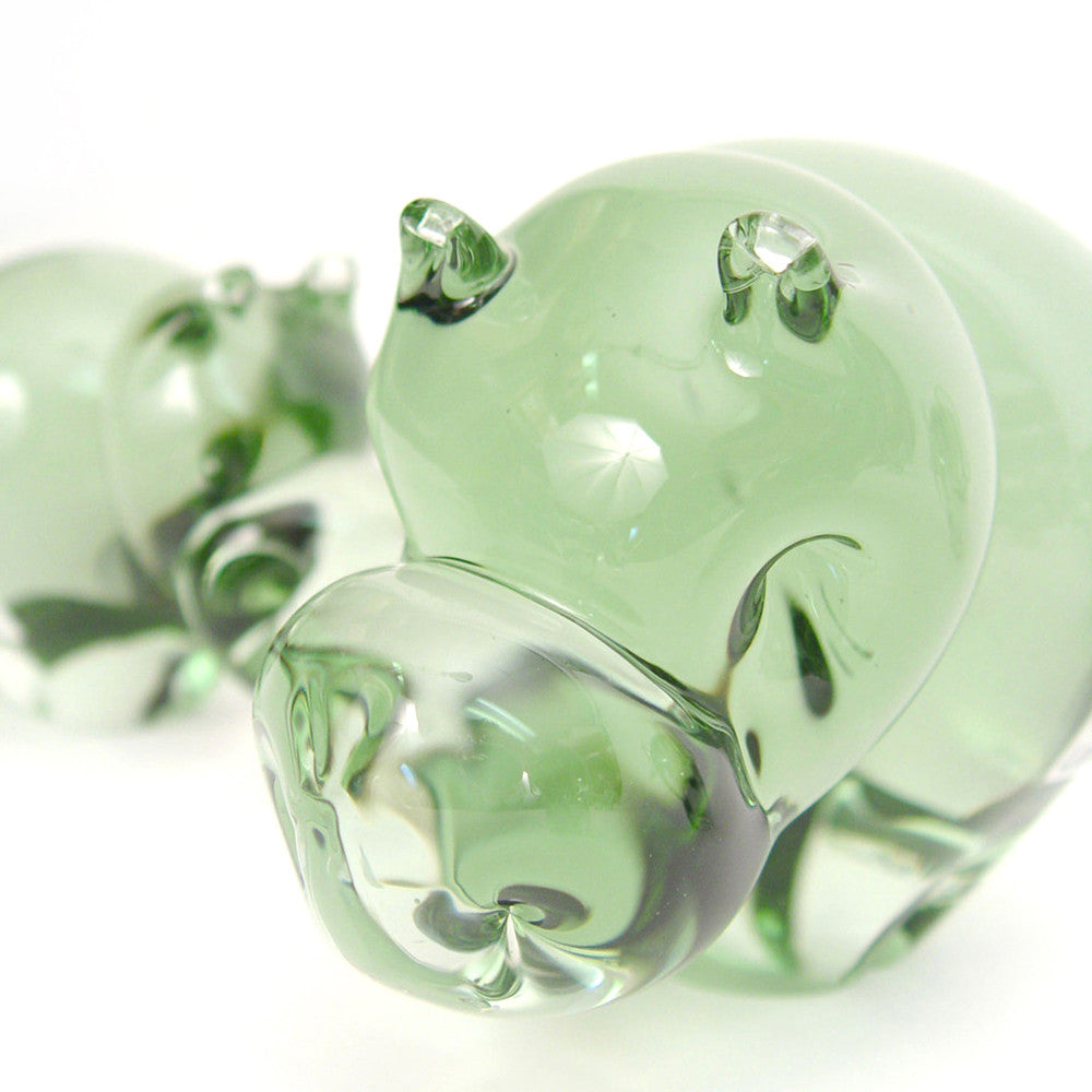 Green glass hippo figurines, close-up of two rounded bodies with glossy raised ears