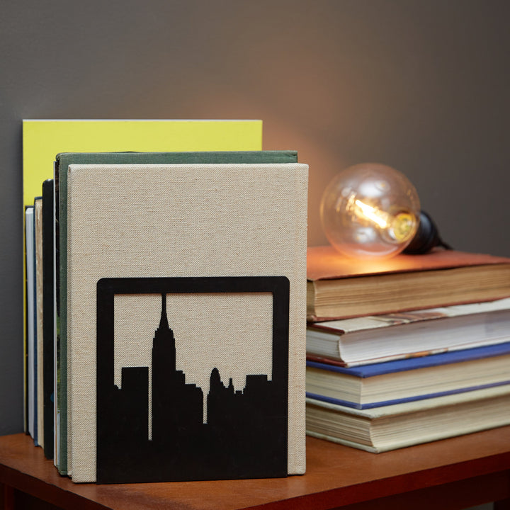 Black NYC skyline metal bookends with open-frame design, holding books on a shelf