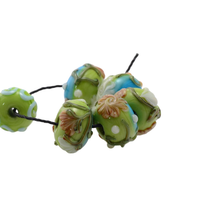 Lampwork glass beads set on black cord, mixed green and blue floral beads