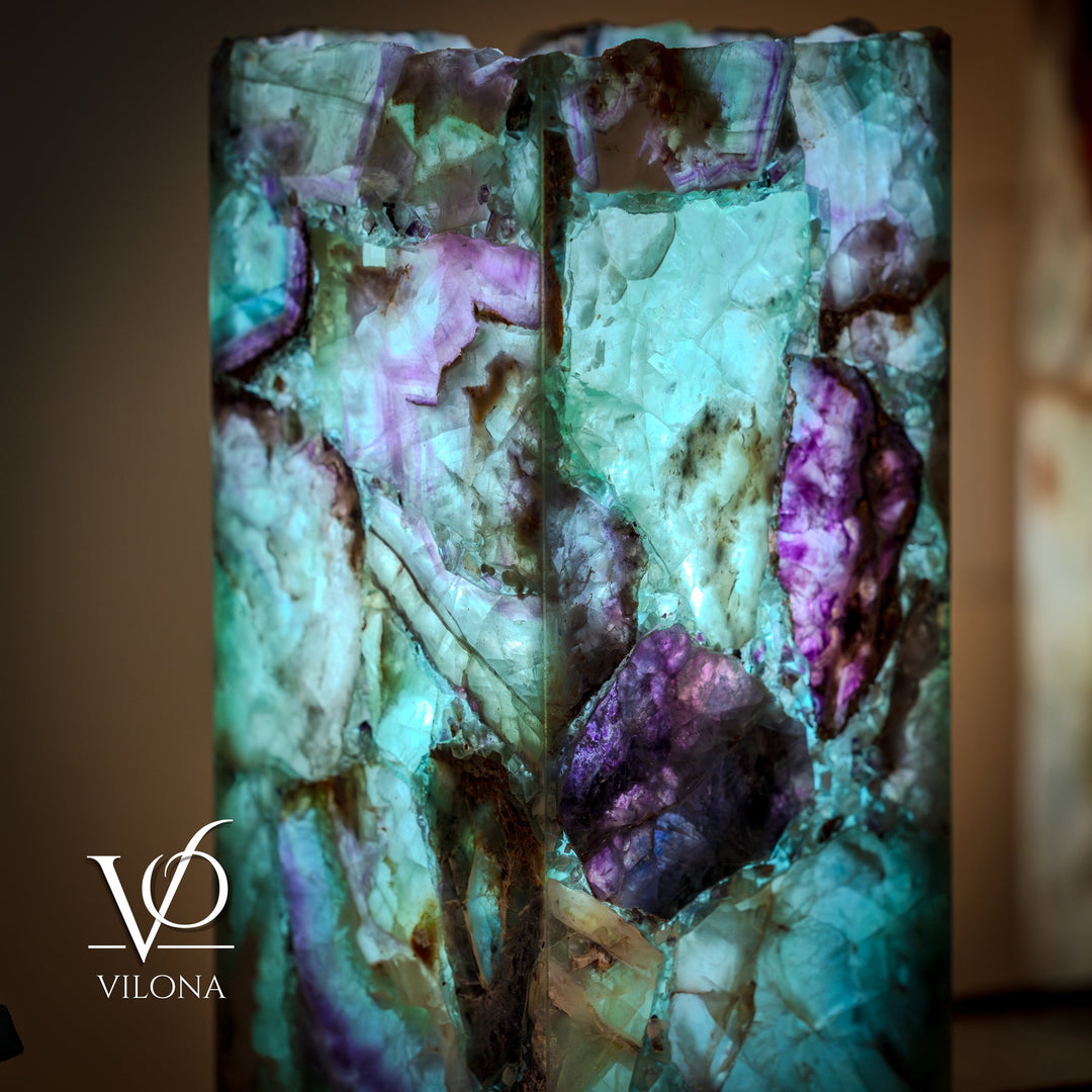 Fluorite table lamp body close-up, translucent teal and amethyst purple facets.