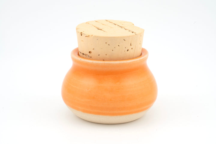 Mini corked jar with orange ceramic glaze and cork lid.