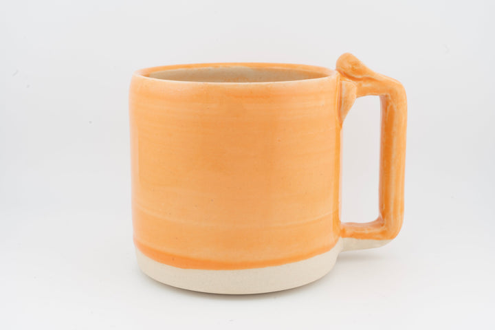 Ceramic mug with orange glaze, right-side handle, and creamy base