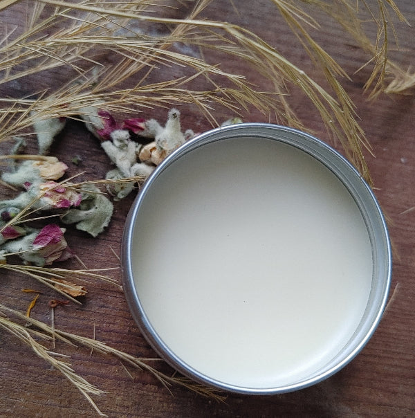 Open metal lip balm tin with smooth white balm inside