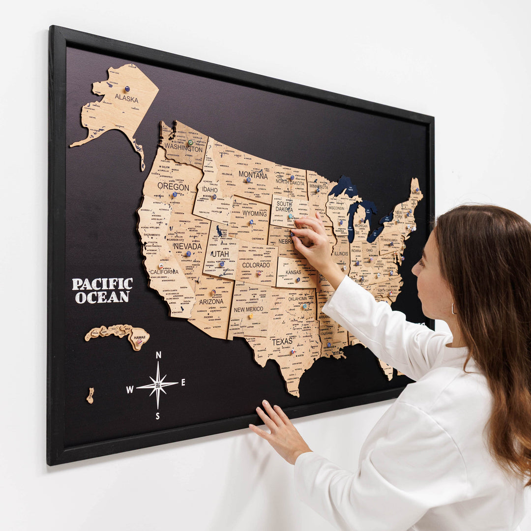 3D wooden USA wall map with raised states on black board, hand adjusting placement