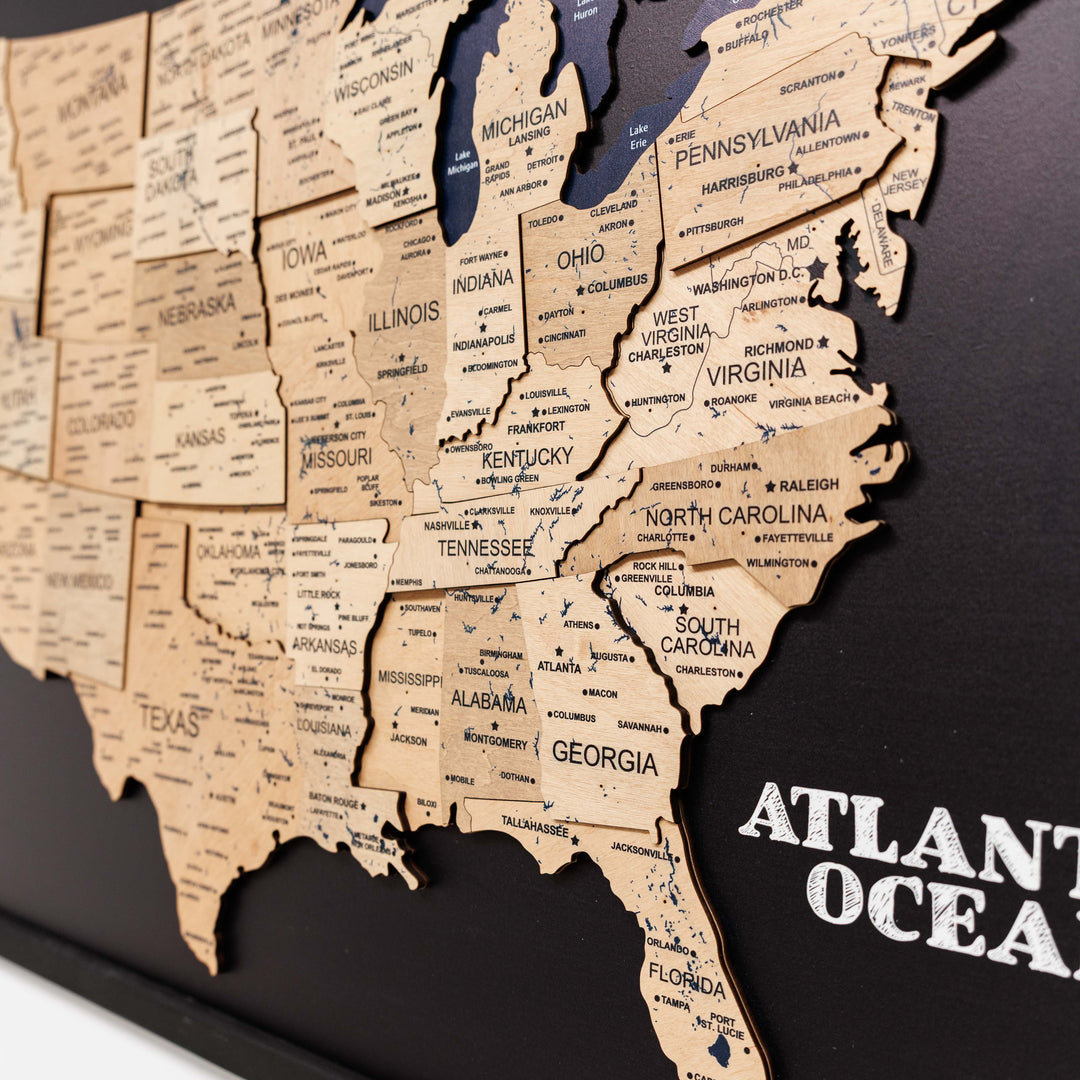Close-up of 3D wooden USA map showing gold-tone states on black board