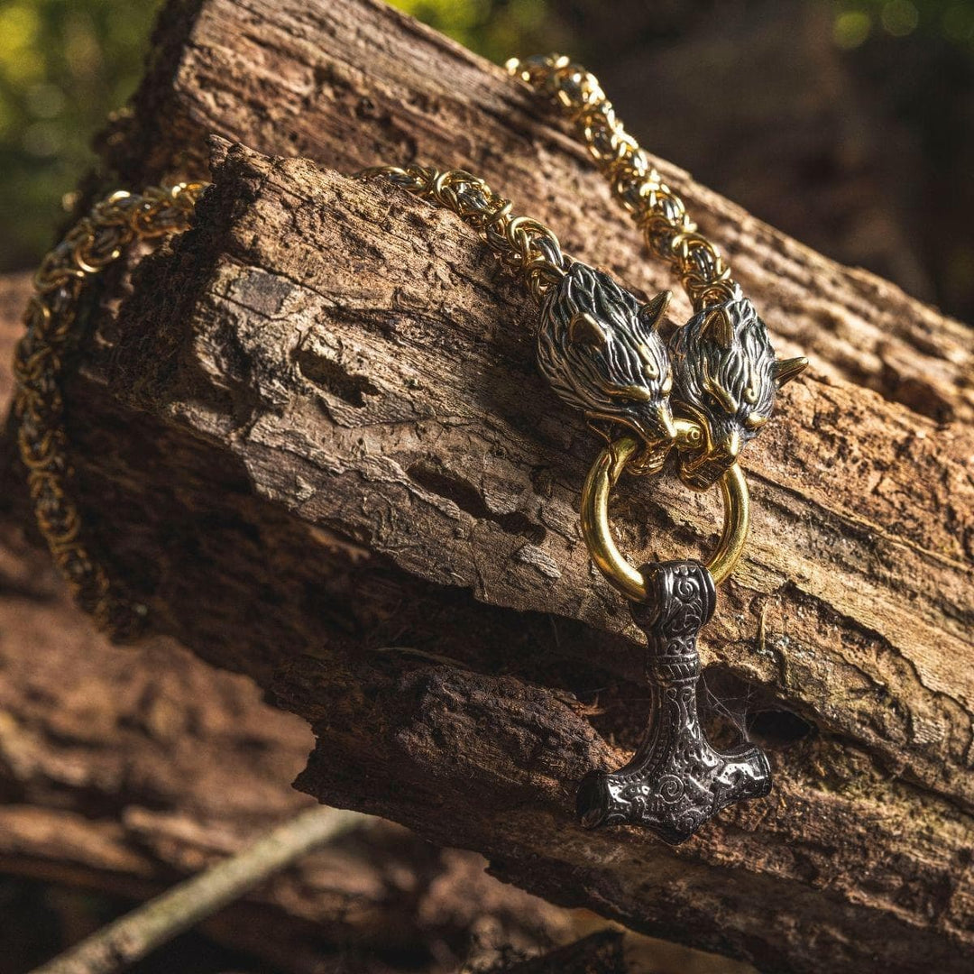 Viking wolf-head Mjolnir pendant necklace on gold-tone chain, posed against wood