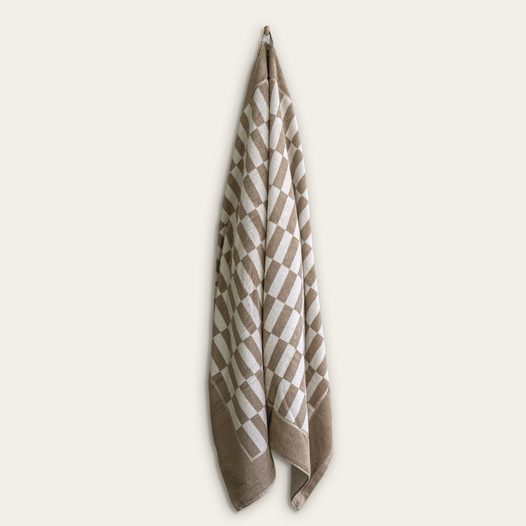 Hanging tan and ecru checkered cotton towel with folded edge