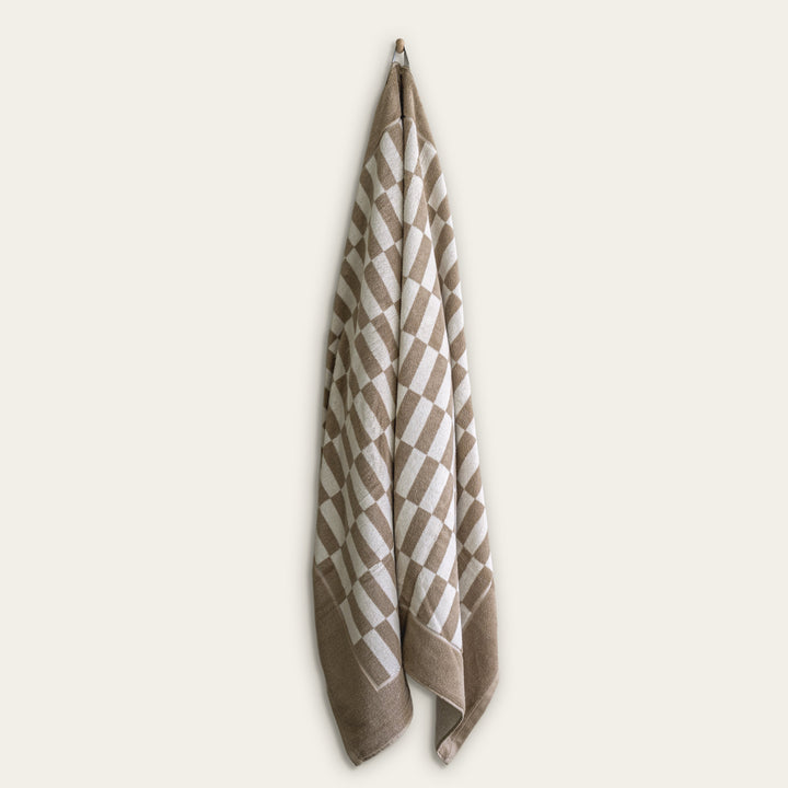 Hanging tan and ecru checkered cotton towel with folded edge