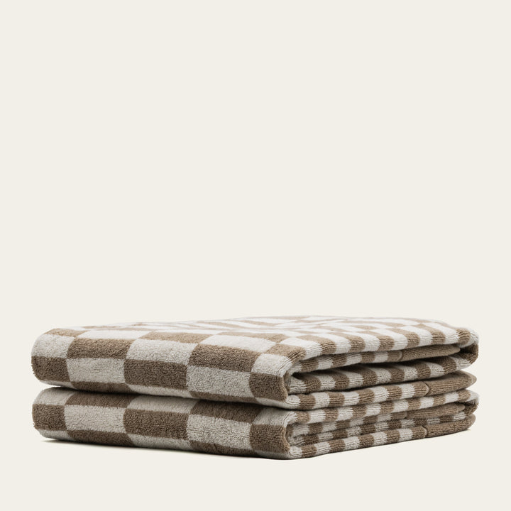 Cotton towels with beige and white stripe pattern, folded neatly in a row