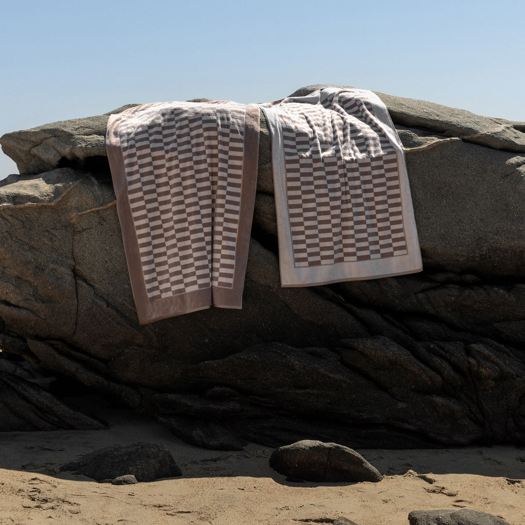 Checkered cotton towels with beige and white borders, folded on dark fabric