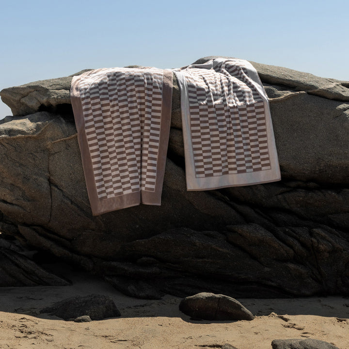 Checkered cotton towels with beige and white borders, folded on dark fabric