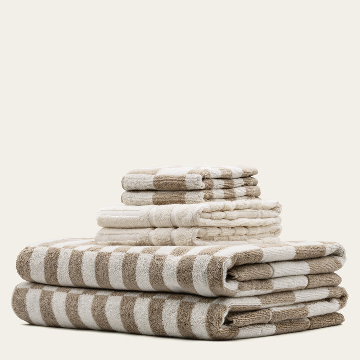 Cotton towels with beige and white stripe pattern, folded in a stack