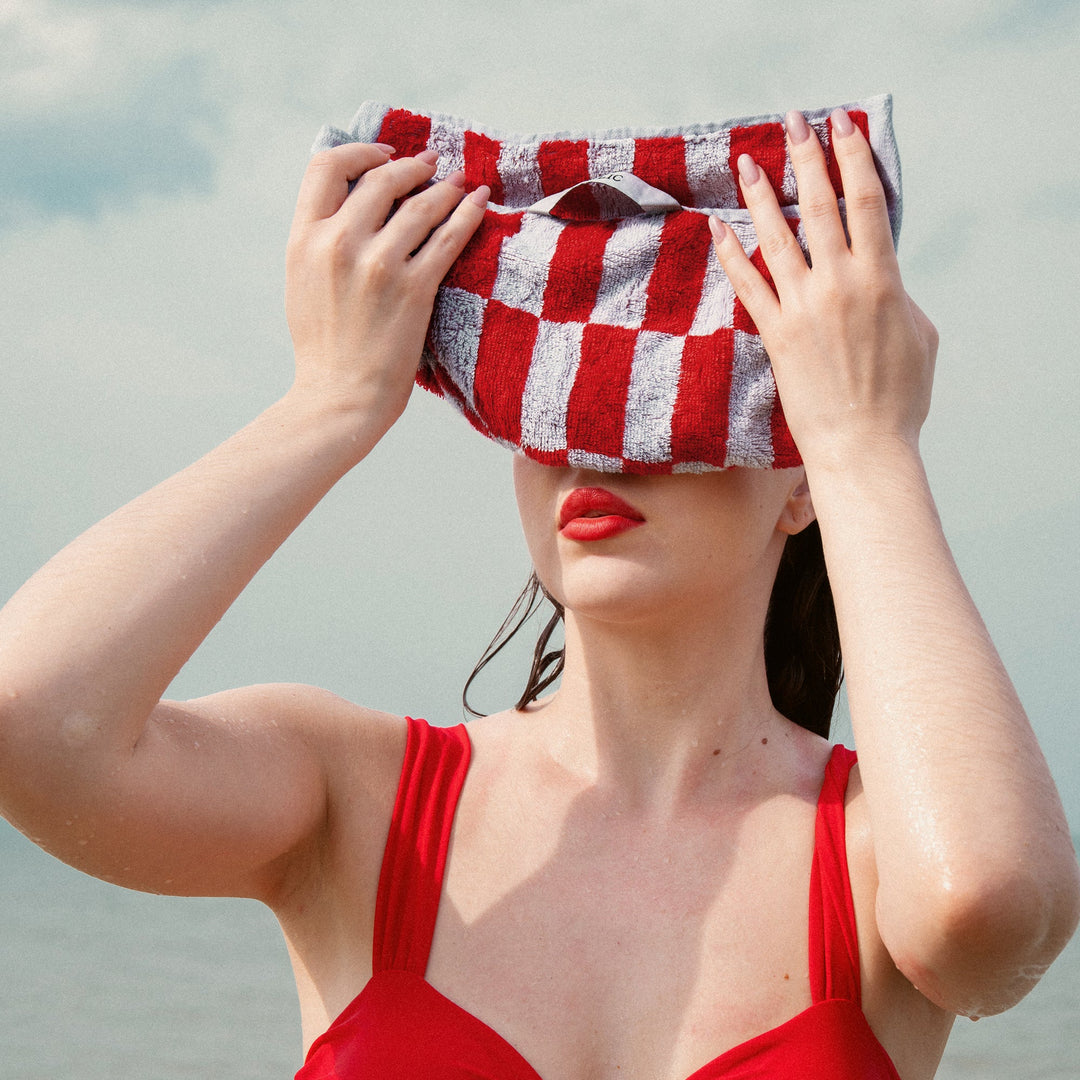 Red and white checkered cotton towel held above head, terry texture visible.