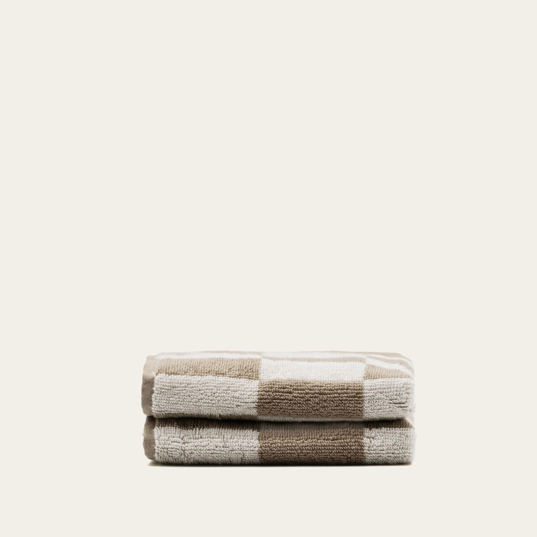 Compact stack of tan and ecru checkered cotton towels, neatly folded