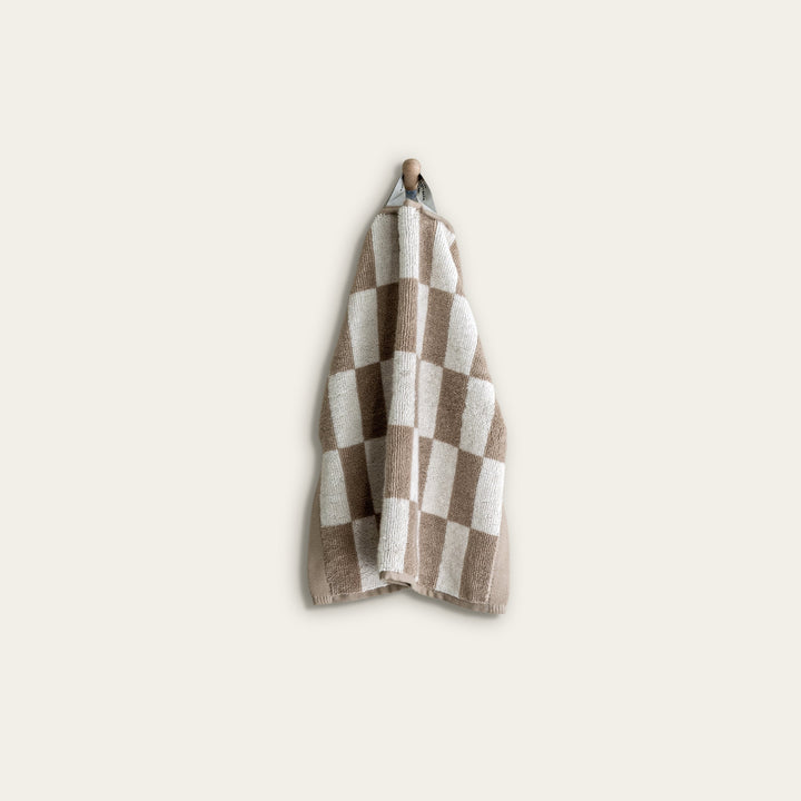 Tan and ecru checkered cotton towel folded and hanging