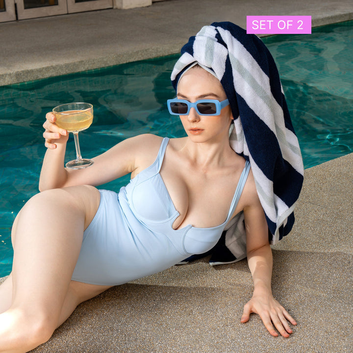 Striped cotton beach towel draped over a swimsuit, navy and white with dark edging.
