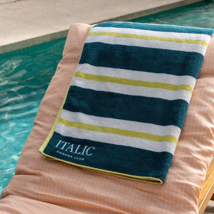 Cotton beach towel with navy, white, and green stripe design, folded with label