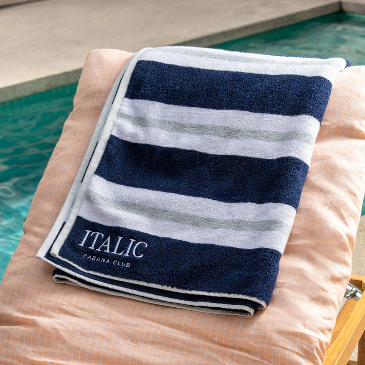 Cotton beach towel with navy and white horizontal stripes, folded with label