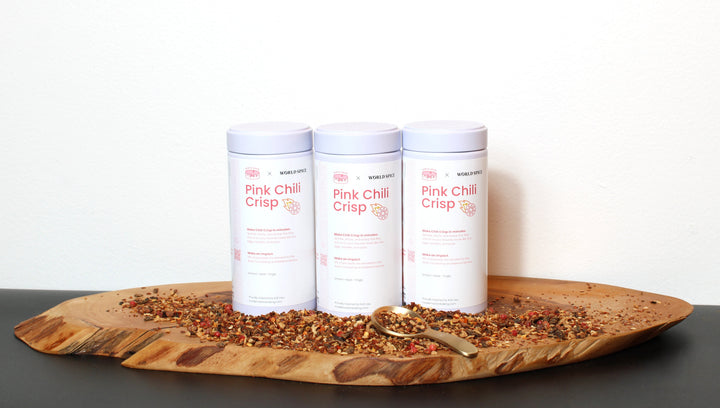 Chili crisp jars with white containers and pink labels; chili topping on wooden board