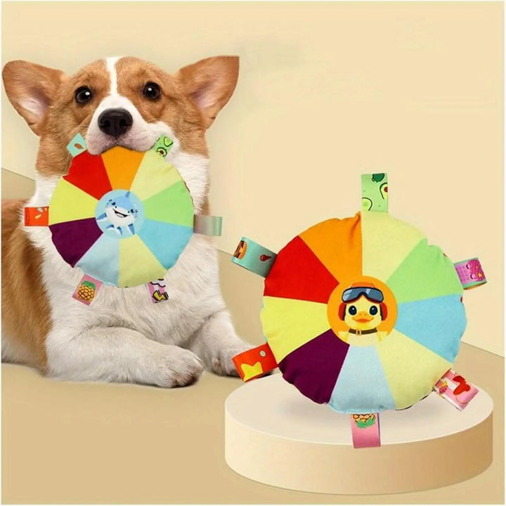 Plush flying disc chew toy with multicolor wheel and dangling fabric tags on a pet