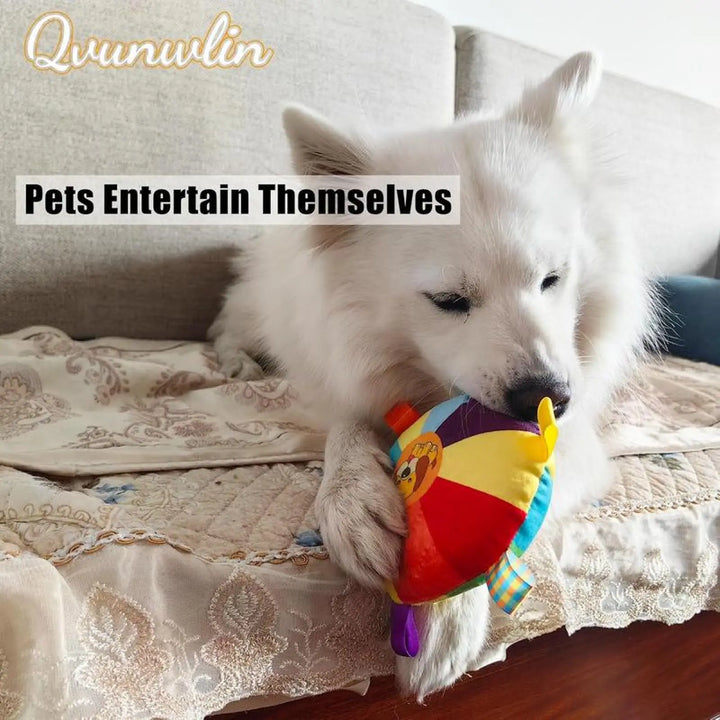 Plush flying disc chew toy with multicolor wheel and dangling fabric tags in a dog's mouth