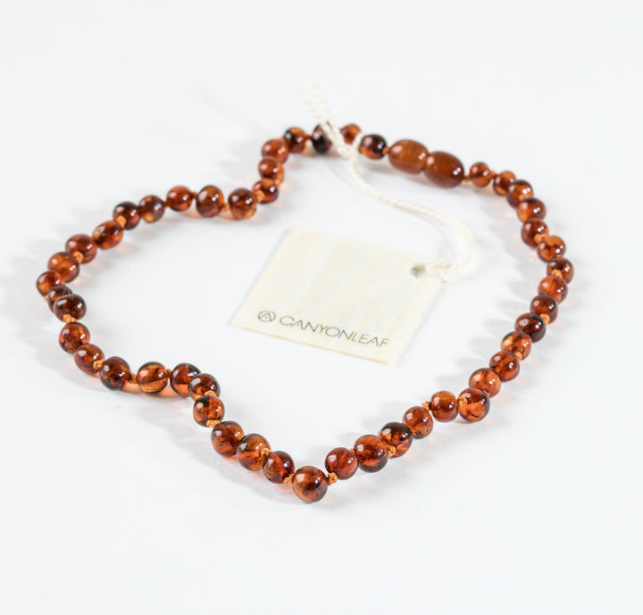 Cognac amber bead necklace with adjustable white cord and small hang tag