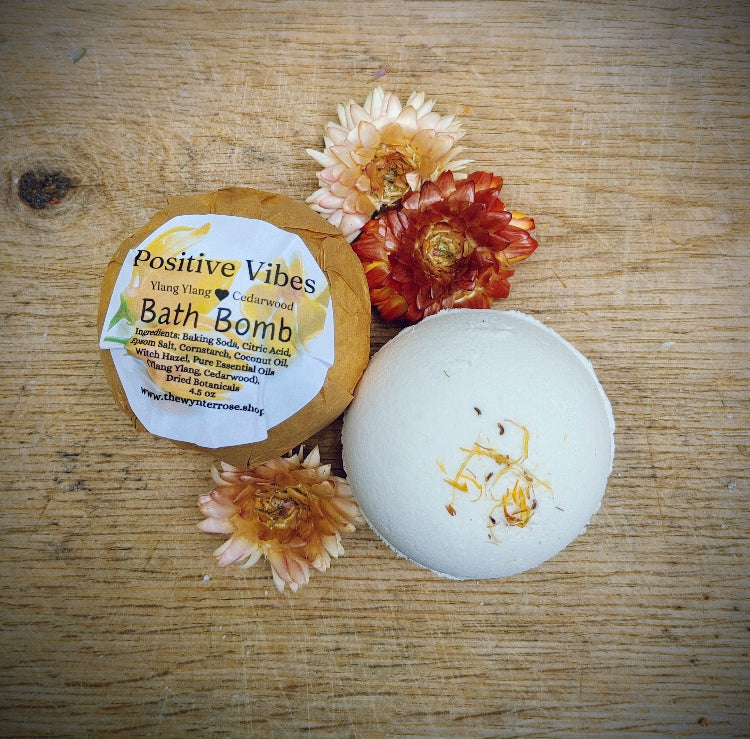 Round white bath bomb with gold specks and a kraft product label