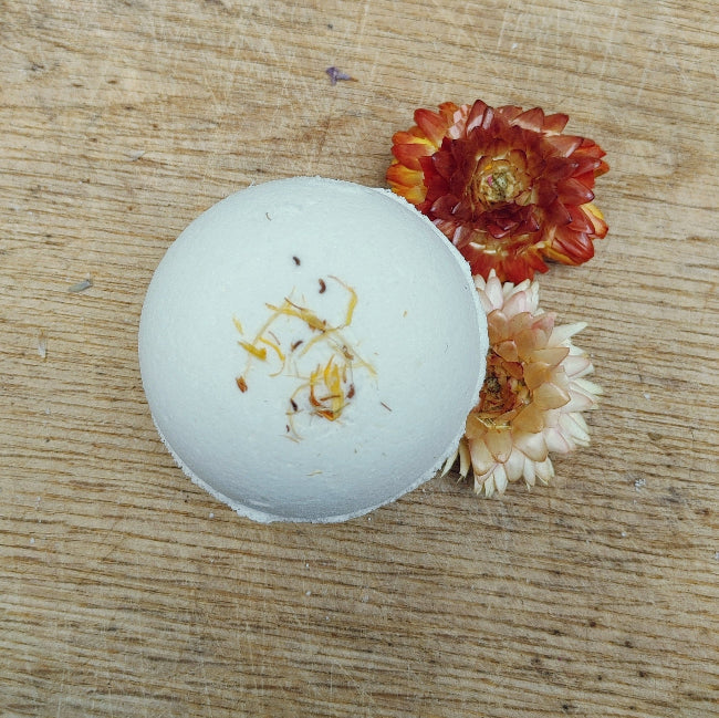 Round white bath bomb with gold specks and red/cream dried flower petals