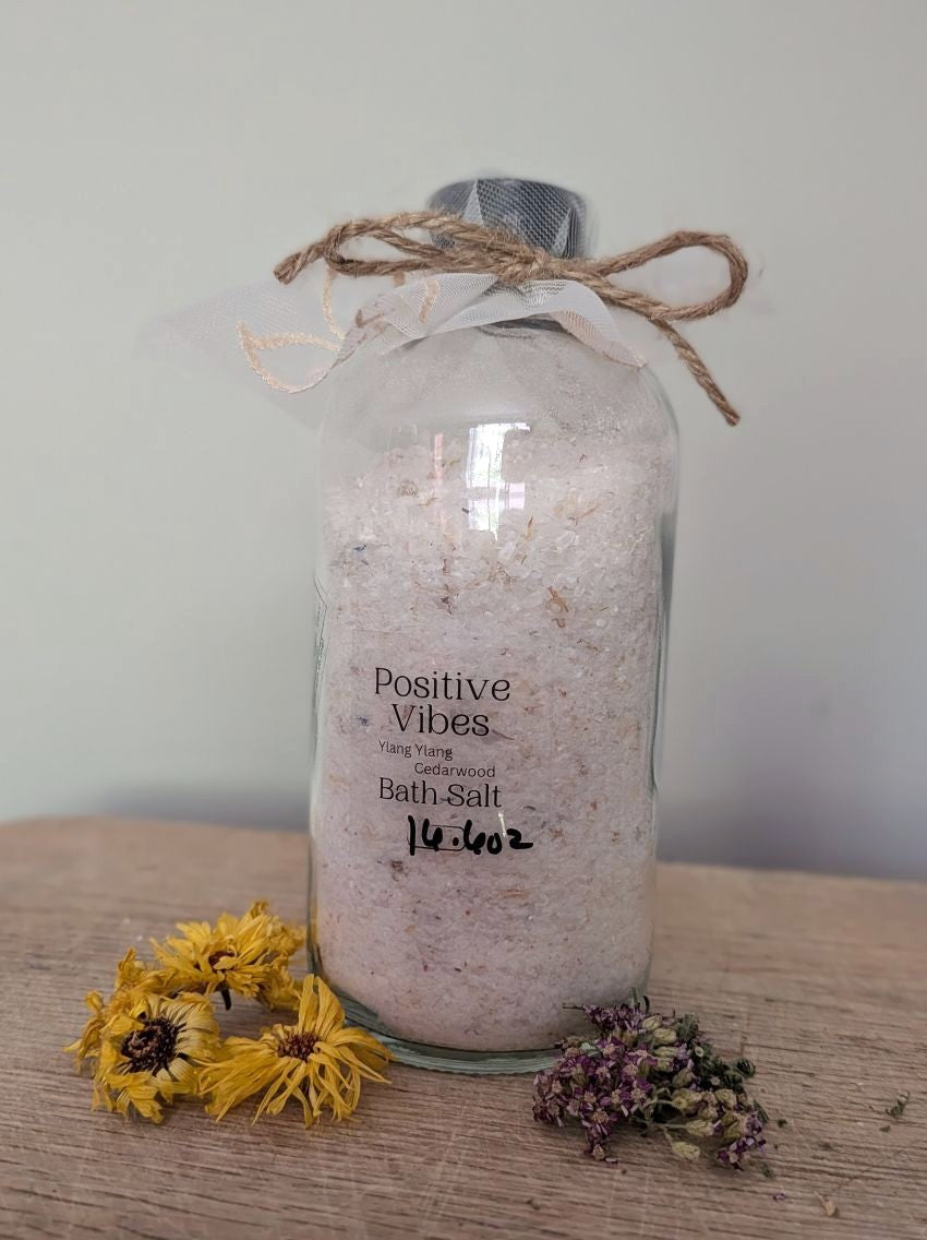 Bath salt bottle with burlap tie, “Positive Vibes” label, pinkish bath salts inside.