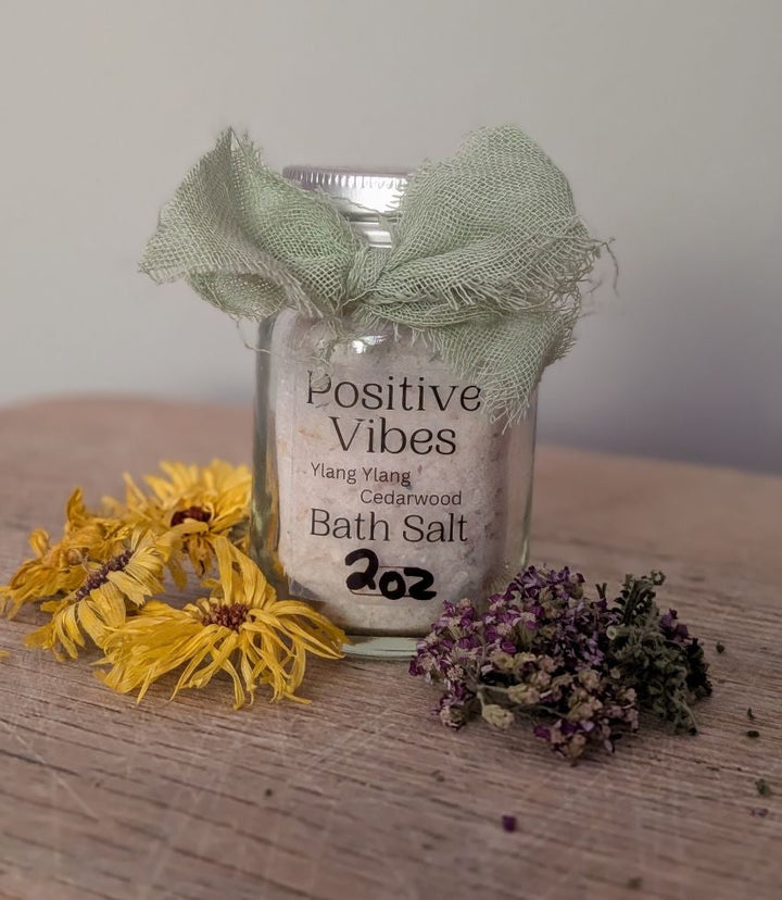Bath salt jar labeled "Positive Vibes" with dried flowers and green fabric bow
