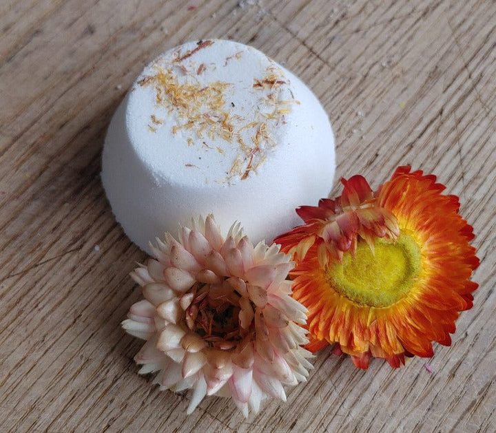White round shower steamer with dried botanicals and two pink flowers