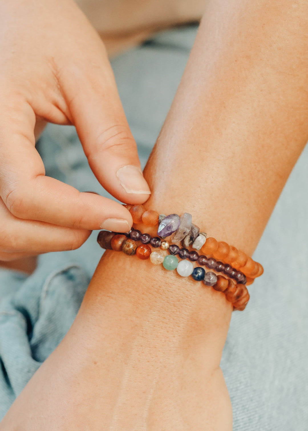 Amber-brown bead bracelet on wrist, paired with purple amethyst and blue beads