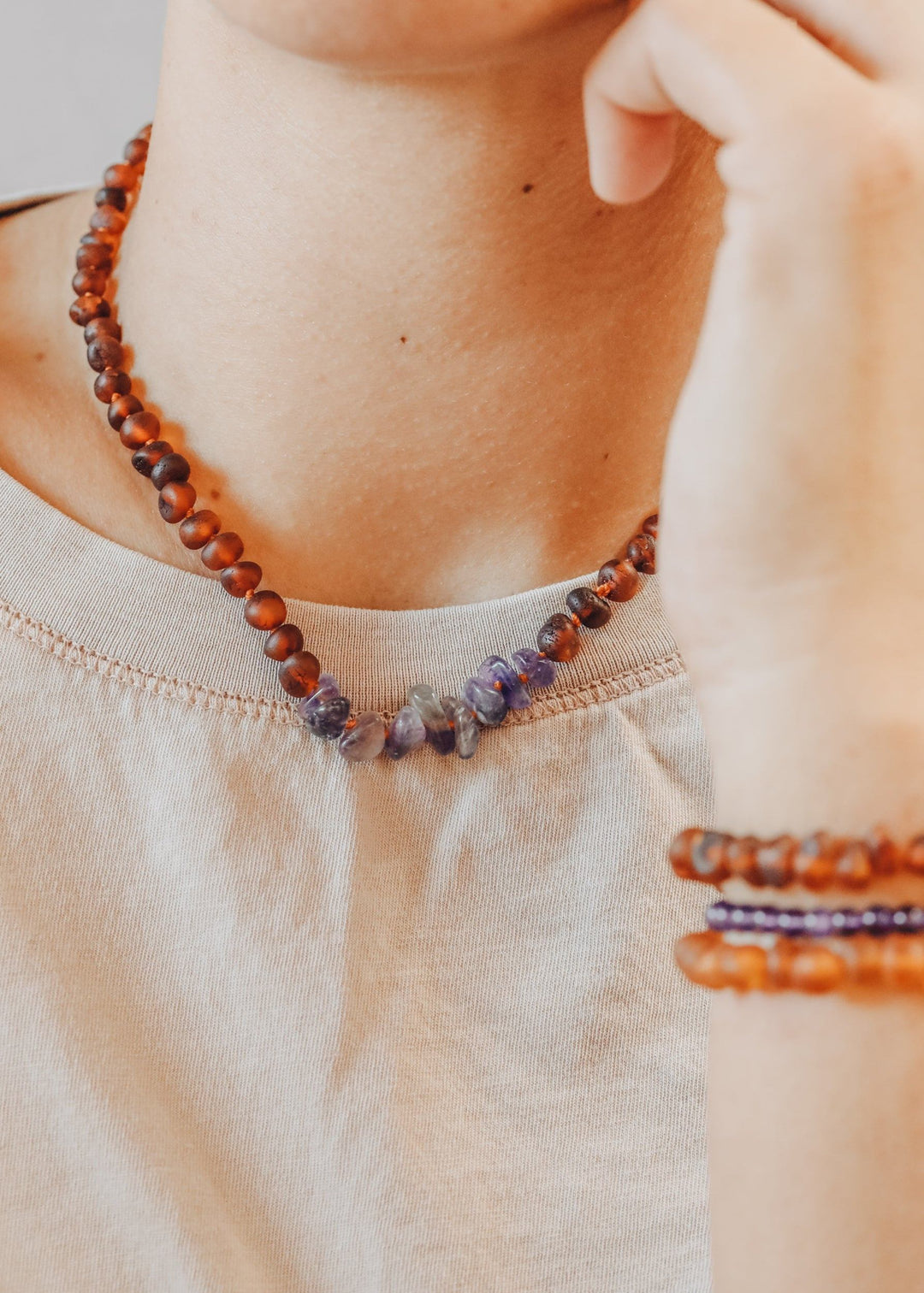 Raw amber and amethyst beaded necklace, worn at the collar on a cream top
