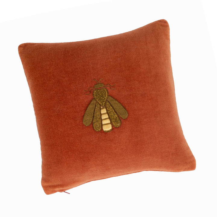 Rust orange velvet throw pillow cover with embroidered bee design, angled view.