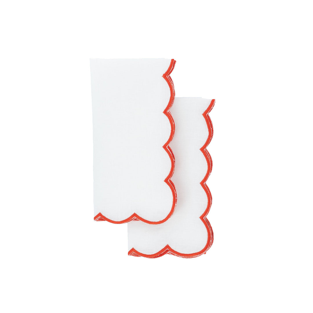 Scalloped linen napkins with red embroidered edges, overlapping upright folds