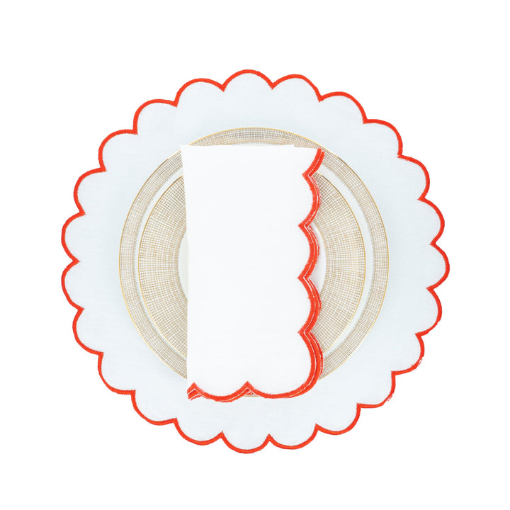 Scalloped linen napkins with red embroidered border on gold-rimmed plate