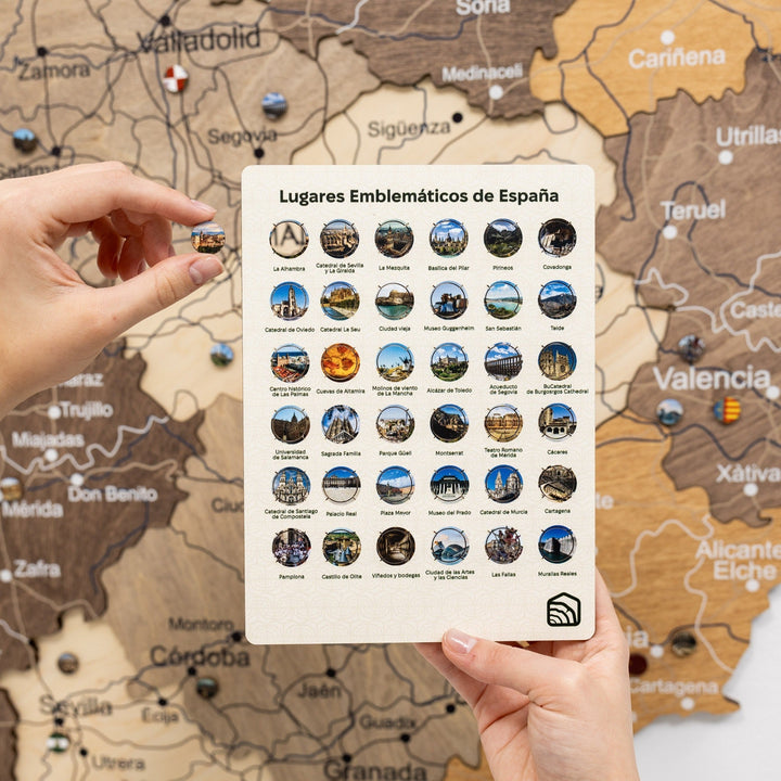 Wooden Spain map with multicolor landmark sticker sheet held in hands
