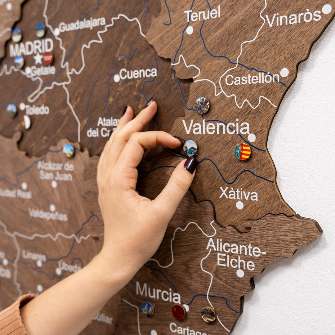 Dark walnut wooden Spain map close-up with Valencia labels and marker pins